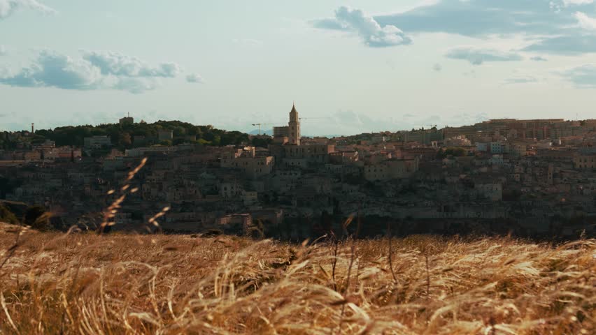 Historic Matera Sassi seen from golden fields in warm late afternoon sunlight in Basilicata, Italy.