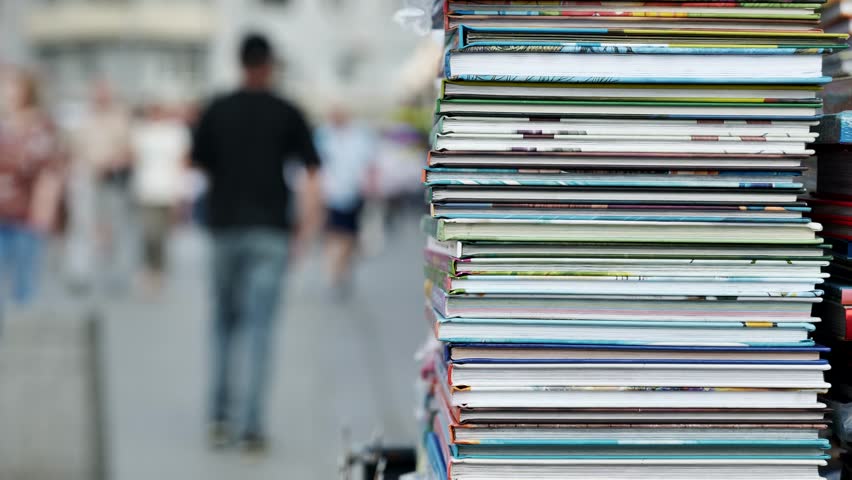 Stack of colorful books forming a tower in a blurred urban street