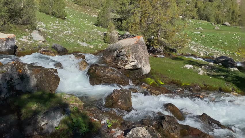Slow motion video of a mountain rushing river in a beautiful remote area of Tajikistan. A trip to the Alaudinsky lakes. Tourism and travel. Freedom and wilderness