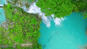 Aerial view of the Agua Azul waterfall cascading into vibrant turquoise pools, surrounded by lush green jungle foliage with people swimming in the water Chiapas, Mexico. - Powered by Shutterstock - Get 15% off with code: PIKWIZARD15