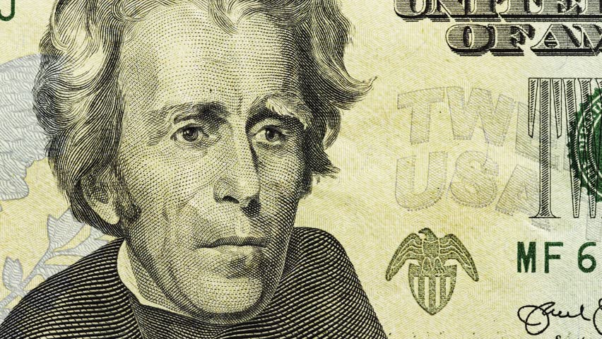Close pan across U.S. twenty dollar note showing portrait, eagle emblem and text
