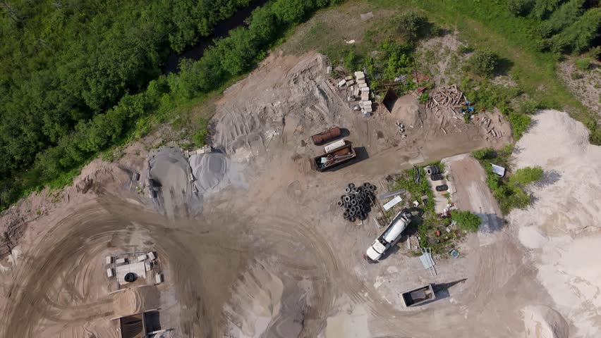 Top down aerial of trucks and machinery at gravel pit in sunny Canada