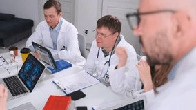 Group of doctors and interns in lab coats discussing brain pathology during residency. Close-up with focus on a bald male doctor while team collaborates on medical education and case reports. - Powered by Shutterstock - Get 15% off with code: PIKWIZARD15