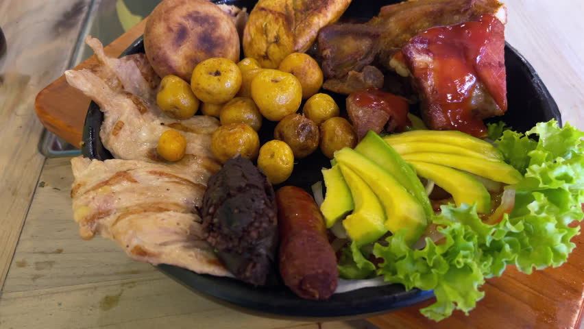 Close up of a Colombian mixed grill platter with arepa, potatoes and salad