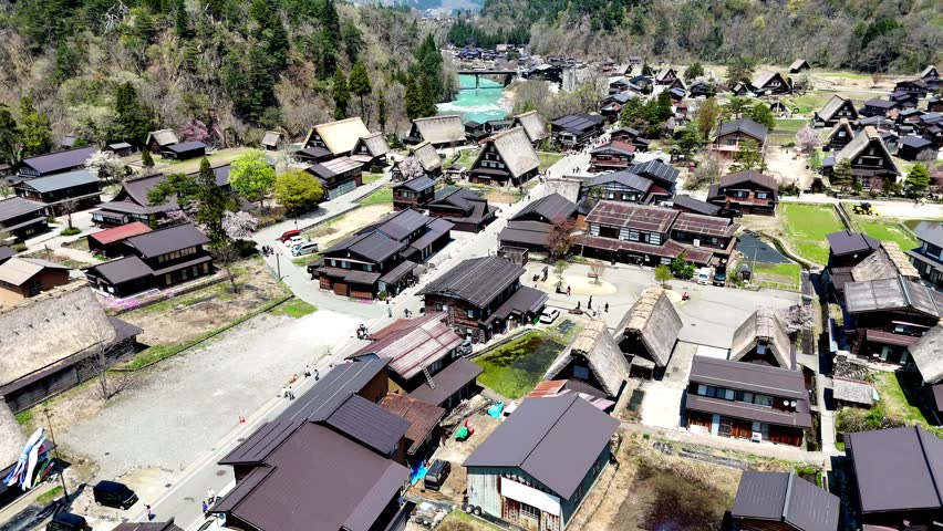 Shirakawago, Japan, Aerial. Flyover of village centre with river in the background
