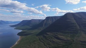 Aerial view along Lake Lama where water meets a towering cliff of the Putorana Plateau in Russia. Summer cloud and shadow over taiga emphasize scale and wilderness for tourism and travel - Powered by Shutterstock - Get 15% off with code: PIKWIZARD15