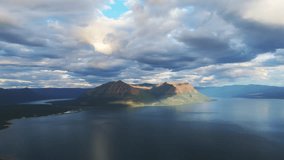 Sunlit island mountain rises from Lake Lama under dramatic cloud, Putorana Plateau, Russia. Evening sun draws warm highlight and cool shadow across the ridge and calm water, ideal for travel promotion - Powered by Shutterstock - Get 15% off with code: PIKWIZARD15