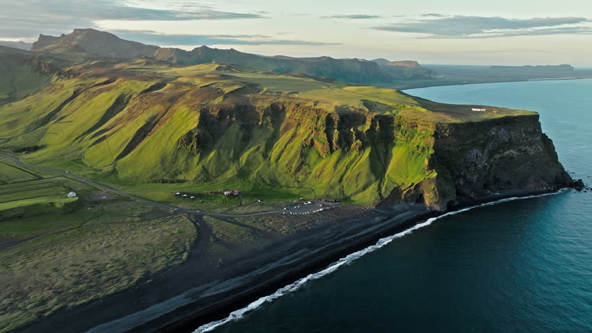 Aerial footage of Reynisfjara Iceland coastline at golden light. Cinematic 4K drone video captures volcanic cliffs, black sand beach, and Atlantic waves in evening tones.