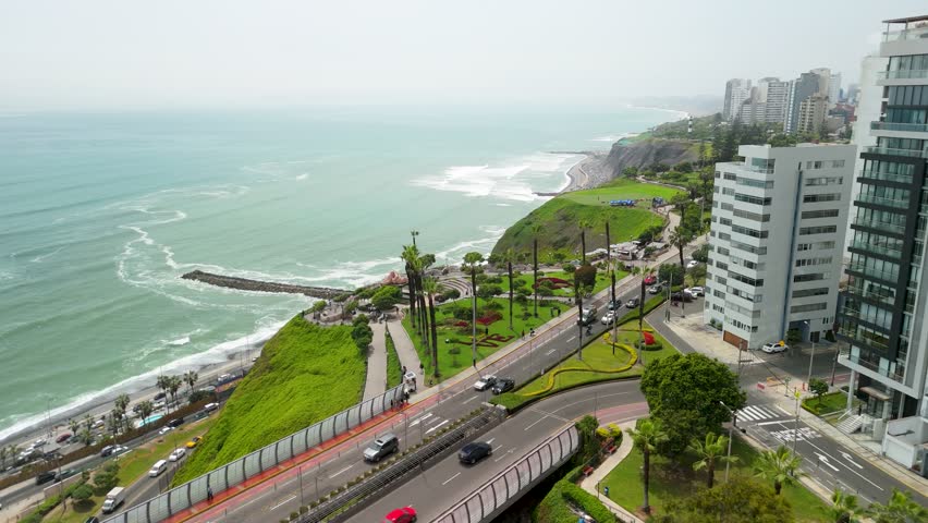 A beautiful aerial parallax shot sweeps over the Parque del Amor on the cliffs of Miraflores, revealing Lima's stunning Costa Verde coastline and the Pacific Ocean