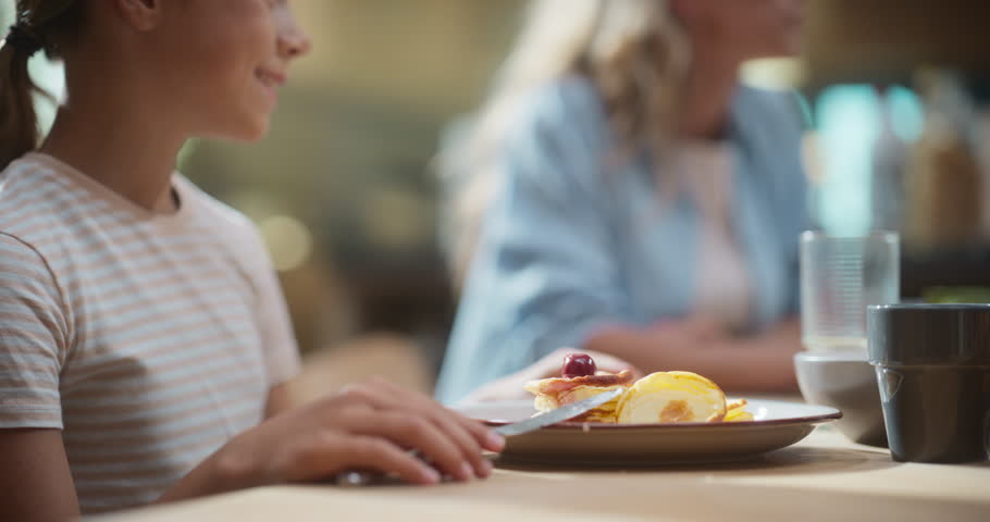Portrait of Girl Eating Pancake Breakfast in a Bright Kitchen. Happy Child Eating Healthy Home Cooked Meal on Fun Sunday Morning.