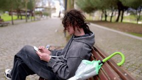 Young man writing on a bench in a park - Powered by Shutterstock - Get 15% off with code: PIKWIZARD15