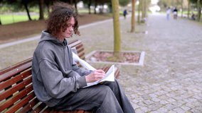 Young man writing on a bench in a park - Powered by Shutterstock - Get 15% off with code: PIKWIZARD15