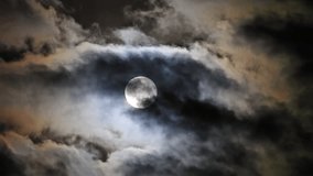 Mysterious view of the full moon partially dimmed by penumbral eclipse, surrounded by colorful dramatic clouds. - Powered by Shutterstock - Get 15% off with code: PIKWIZARD15