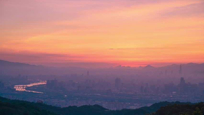 Early autumn dawn from Dadao Mountain, Taiwan. Witness the full sunrise over a hazy Taipei City, enveloped in a dreamlike landscape of orange, pink, and white clouds.