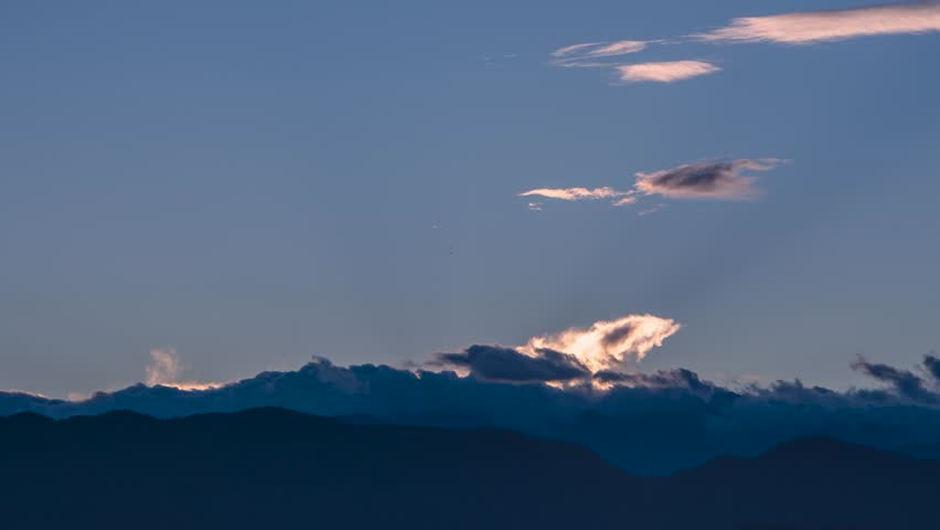 Soft sunrise emerging from clouds over mountains in Taiwan. Gentle, rolling clouds in a peaceful early autumn morning.