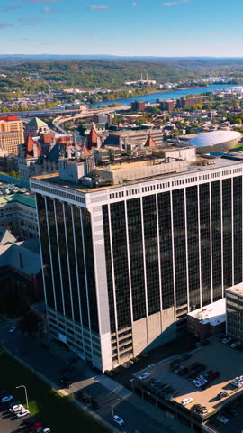 Albany cityscape with autumn foliage. Modern and historic buildings in the city center on the banks of the Hudson River with bridges. Aerial view. Vertical video.