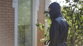 Girl dressed in black leather coat and mask acts as a thief, using flashlight to peek through house window, symbolizing burglary attempt. - Powered by Shutterstock - Get 15% off with code: PIKWIZARD15