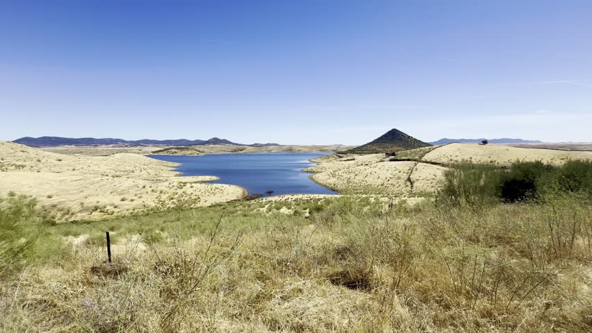 Wide landscape of Cerro Masatrigo above La Serena reservoir in Extremadura, Spain. The shoreline curves add harmony to this peaceful natural panorama.