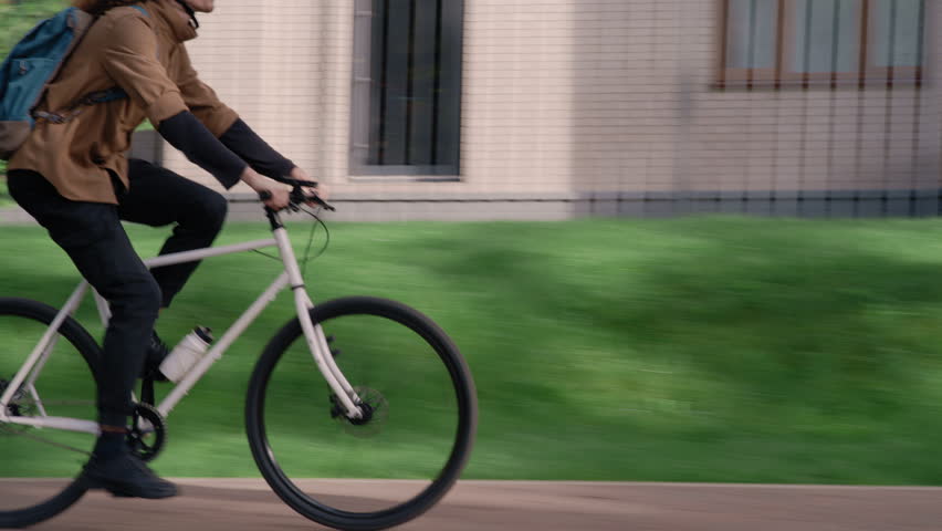 Lifestyle shot of a young biker passing greenery and houses in a peaceful, well-maintained area.
