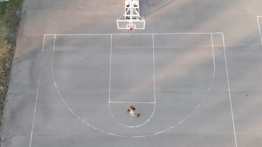 Kid playing basketball at playground aerial view