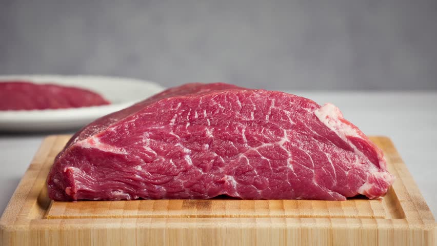 chef cut meat on cutting board with sharp knife for making healthy meal and cooking, chef cutting raw meat into pieces, slicing for steak. Beef fillet langet, food closeup