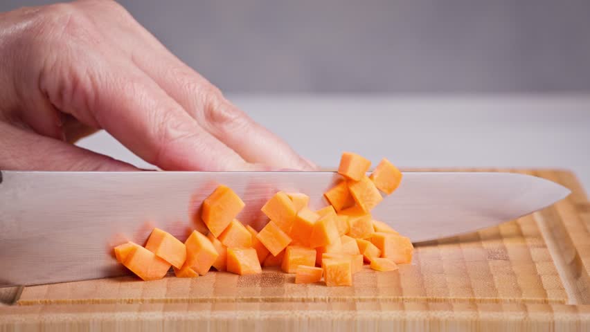 chef cut carrot on cutting board with sharp knife for making healthy meal and cooking, cook cutting carrots for making salad, food closeup in kitchen