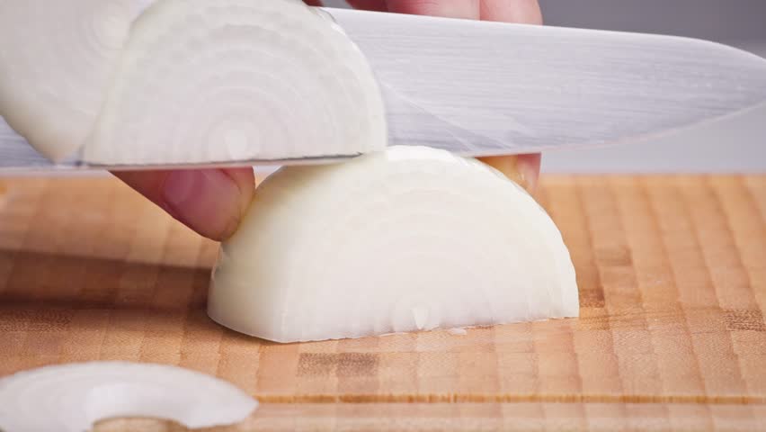 chef cut onion on cutting board with sharp knife for making healthy meal and cooking, cook cutting white juicy onions for making salad, food closeup in kitchen