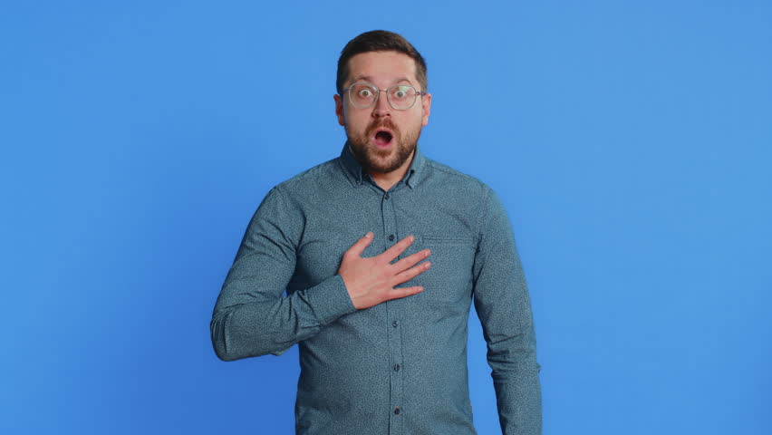 Oh my God, Wow. Excited amazed winner man raising hands in surprise looking at camera with big eyes shocked by sudden victory celebrating success achievement good news. Guy on blue background
