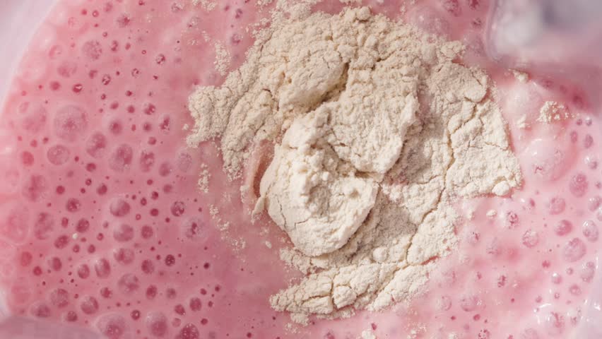 Strawberry and banana pink milkshake blended in blender with splashes. top view. slow motion. Healthy protein smoothie drink concept , food closeup. Protein powder in smoothie