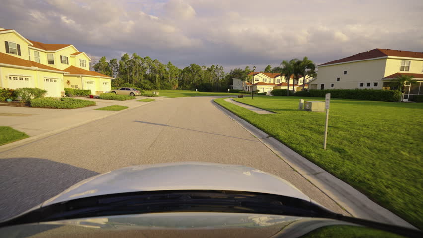 POV car driving on town street in USA. Suburban American street between condo buildings in Florida residential area.