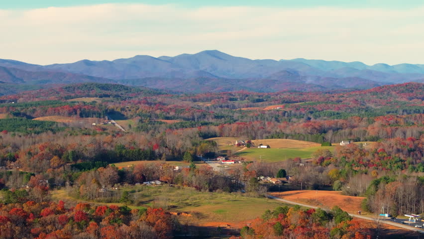 Remote rural homes nestled among the fall season red trees in Tennessee. Autumnal Appalachian woods with golden and amber tree crowns.