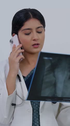 Vertical Video of Indian Female Doctor Looking at X Ray Report and Talking on Phone