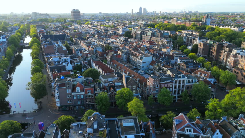 Breathtaking aerial shots showcasing picturesque Amsterdam canal houses and the vibrant green trees of Amsterdam, effectively capturing the city unique and unparalleled architectural beauty and charm