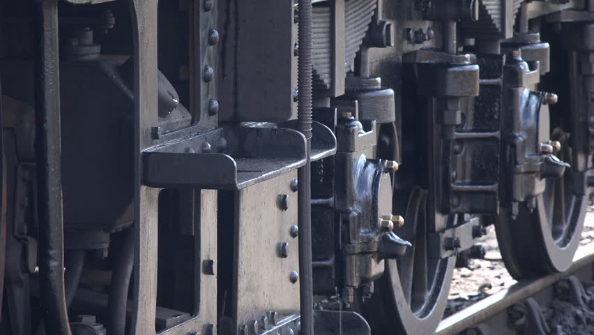 Close up of steam train wheels and smoke coming from pipes as locomotive gets ready to move from station. Transport traditional and old in a historic railway for tourism England UK 4K 
