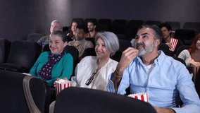Senior couple sharing laughter and popcorn during cinematic experience, enjoying movie night with warm connection in darkened theater environment - Powered by Shutterstock - Get 15% off with code: PIKWIZARD15