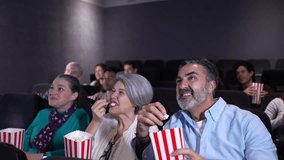 Senior couple pointing and laughing while watching a movie at the cinema, eating popcorn in slow motion - Powered by Shutterstock - Get 15% off with code: PIKWIZARD15