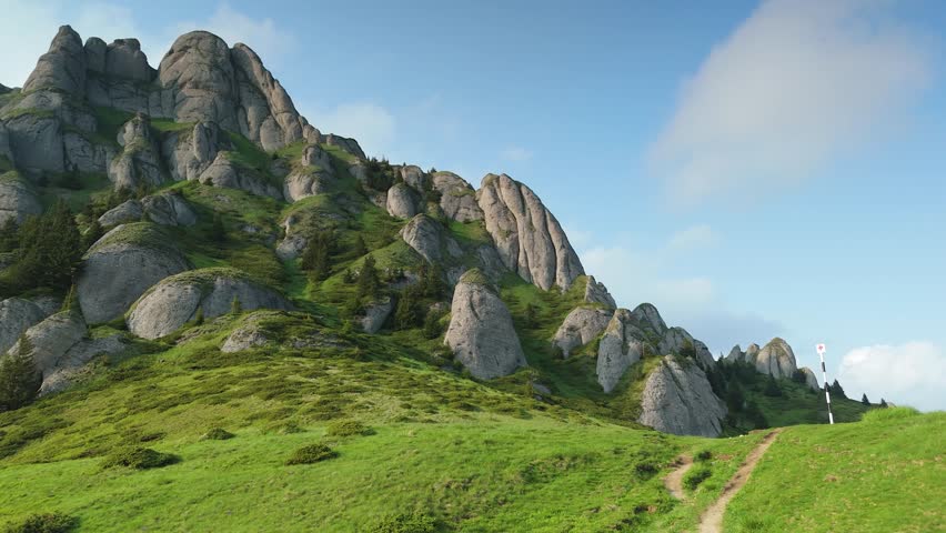 Hiker admiring dramatic rock formations of Tigaile Mari in Ciucas Mountains at summer sunset, scenic mountain landscape in Romania