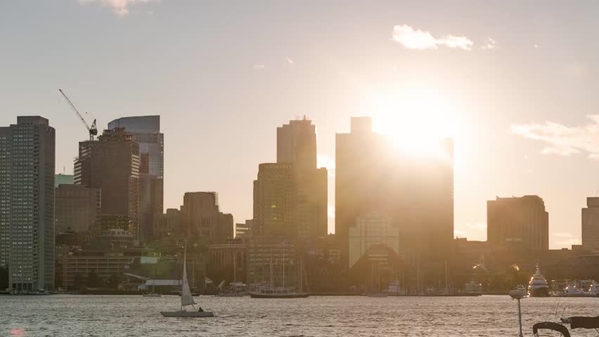 Boston. Aerial view of a city skyline during sunset, with the sun casting a warm, golden hue over the scene.