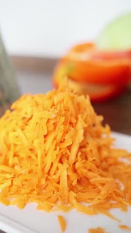A plate featuring vibrant, shredded carrots beautifully arranged, alongside bell peppers and cabbage in the background. Slow motion