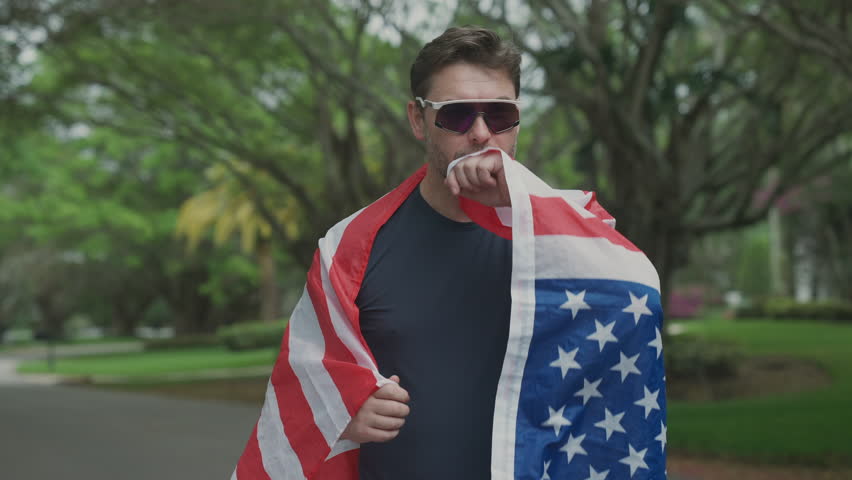 Runner wraps himself in United States flag and kisses it proudly after crossing finish line. Male athlete symbolizes victory, patriotism, and celebration of first place achievement. - Powered by Shutterstock - Get 15% off with code: PIKWIZARD15