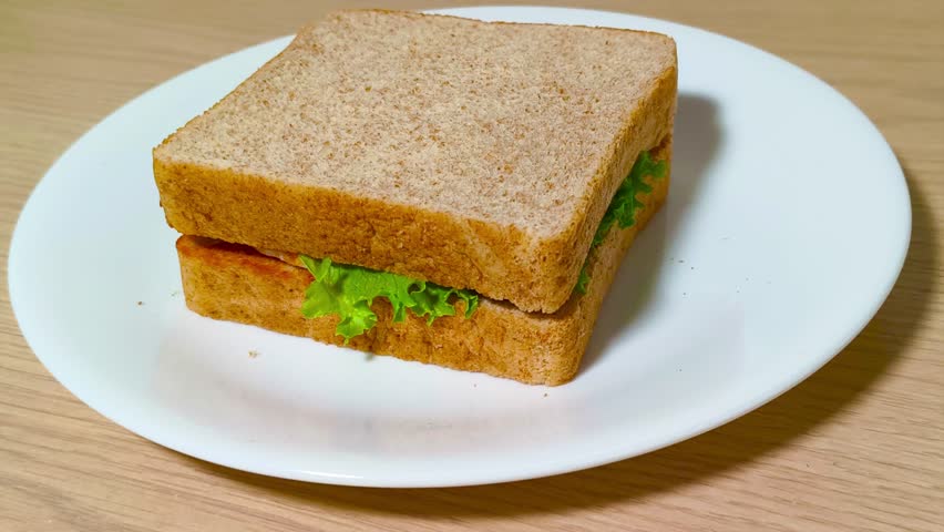 Fresh delicious vibrant tasty sandwich with crisp lettuce on a plate on a rustic wooden table. Healthy lunch, savory meal, fresh ingredients, wholesome, colorful, appetizing.