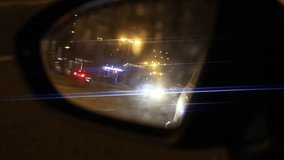 Niight city traffic reflected in a car side mirror with bright headlight glare and blue lens flares. Urban driving at night, safety and transportation concept. - Powered by Shutterstock - Get 15% off with code: PIKWIZARD15
