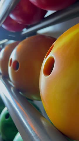 Bowling balls lined up on a rack, ready for play. Concept of recreational bowling, leisure time, and waiting for the next strike