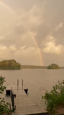 Vertical screen rainbow over scenic nordic lake travel destination pure nature stunning landscape authentic experience explore northern europe adventure stock video