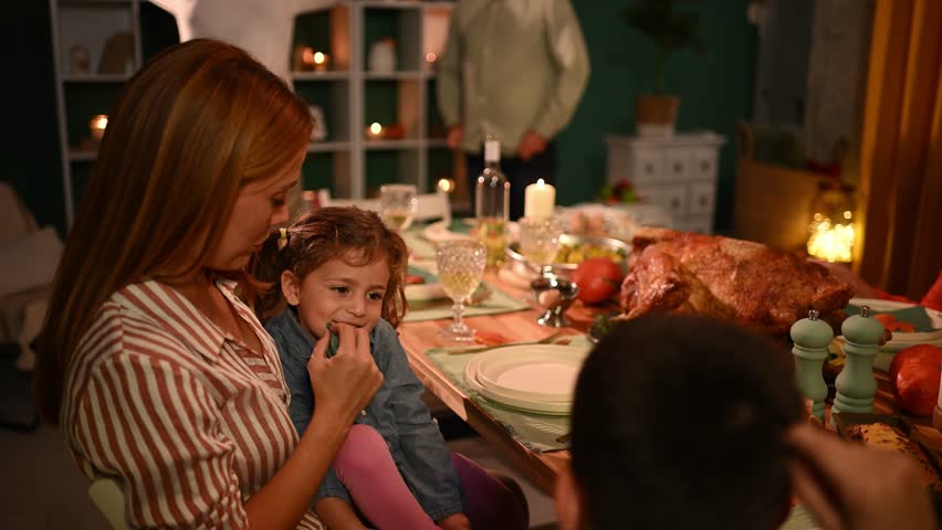 Mother and daughter share a tender moment during thanksgiving dinner, surrounded by family and a festive atmosphere
