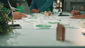 A diverse business team collaborates in a modern office, reviewing sustainable development plans with charts and models, highlighting eco-friendly strategies for growth. SACTR - Powered by Shutterstock - Get 15% off with code: PIKWIZARD15