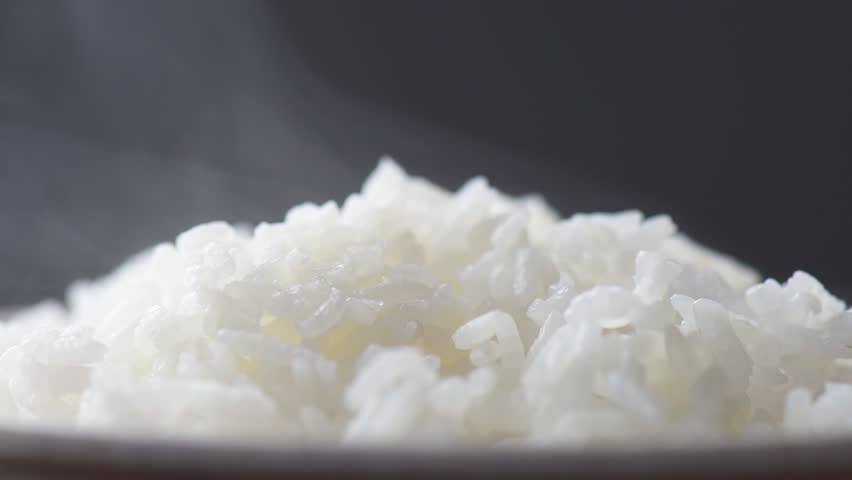 Freshly brewed hot fragrant rice. Macro shot. Bowl of Jasmine rice. Closeup view of long-grain variety of aromatic rice. Healthy eco food. Product of organic farming.
