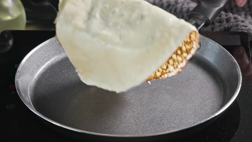 cook turn around pancake on frying pan. closeup of freshly baked crepe on hot frying pan in kitchen. process of making delicious pancakes at home for healthy breakfast, food close up