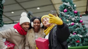 Cheerful multiethnic friends capturing memorable selfie moment at festive christmas market, wearing warm winter clothing and sharing joyful holiday experience - Powered by Shutterstock - Get 15% off with code: PIKWIZARD15