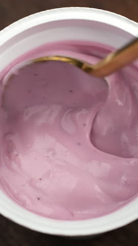 Eating fruit yogurt. Healthy blueberry Yogurt Dessert stirred with Spoon